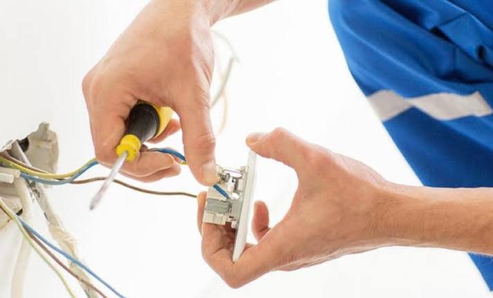 Electricista conectando una llave de luz de combinación en la pared de una casa de CABA