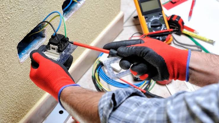 Electricista usando un tester para medir tensión antes de manipular cables en una instalación de CABA