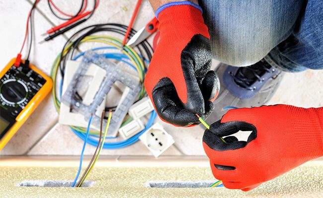 Electricista instalando un tomacorriente embutido en el piso del living de una casa en CABA