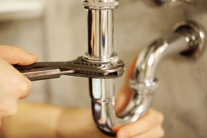 Llave ajustando el sifón cromado del baño bajo la bacha en una casa de CABA